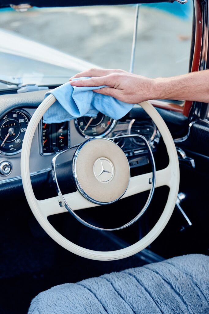 Hand wiping a steering wheel with a cloth in Magic Hand Car wash store in Southport