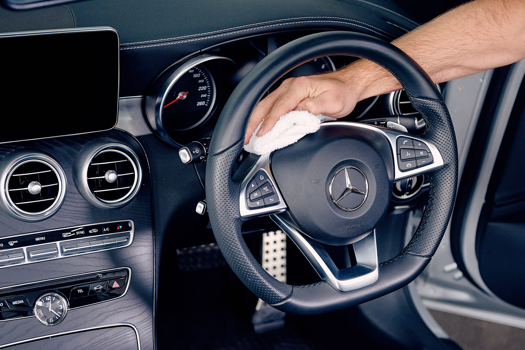 A hand wiping a steering wheel with a white towel-Interior detailing