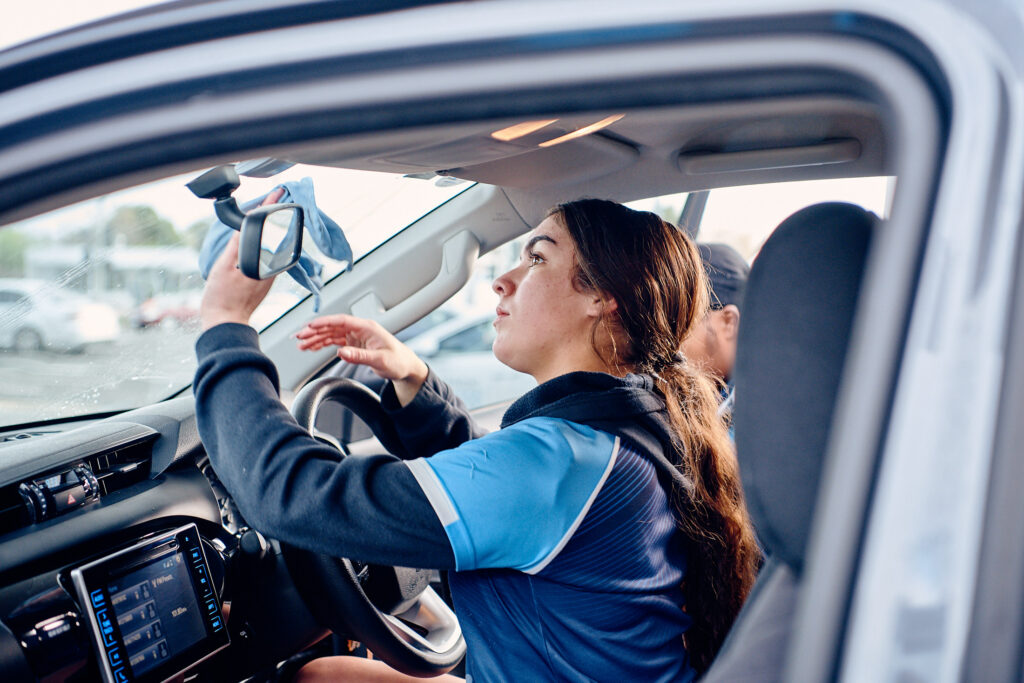 A woman cleaning the inside of a car window